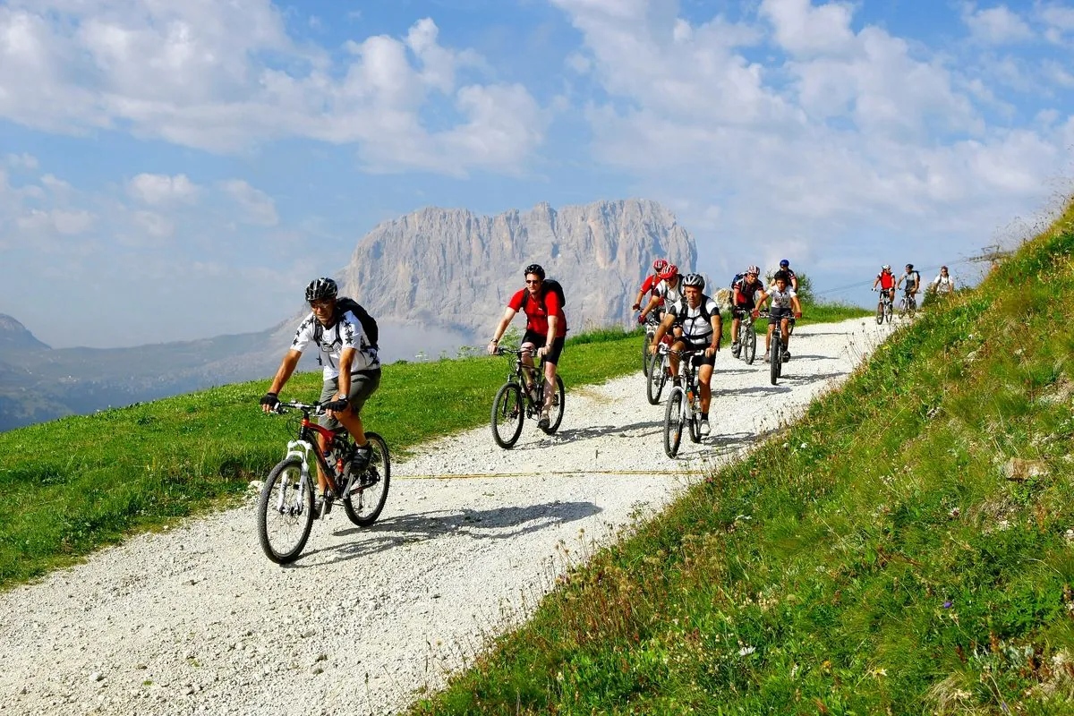 Mountainbiker auf einem Almweg, dahinter Dolomitenfelsen
