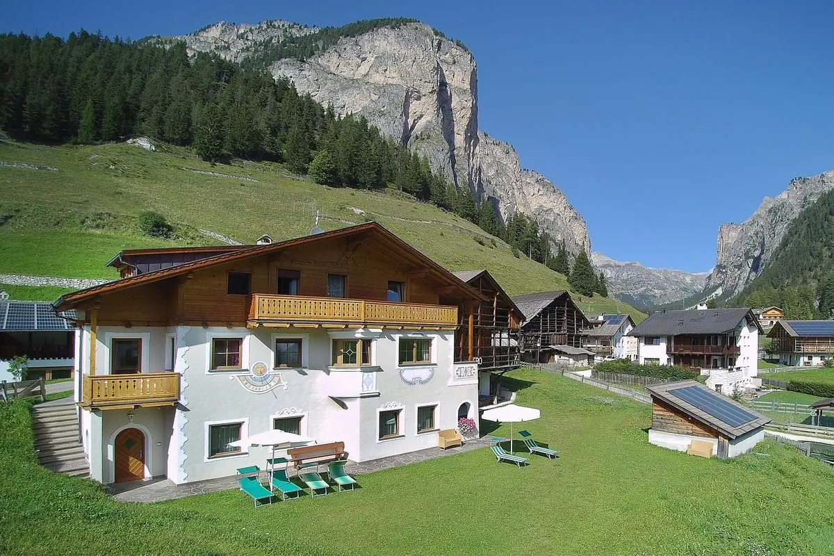 Die Dependance im Sommer neben La Majon, mit Holzbalkon und Wiese