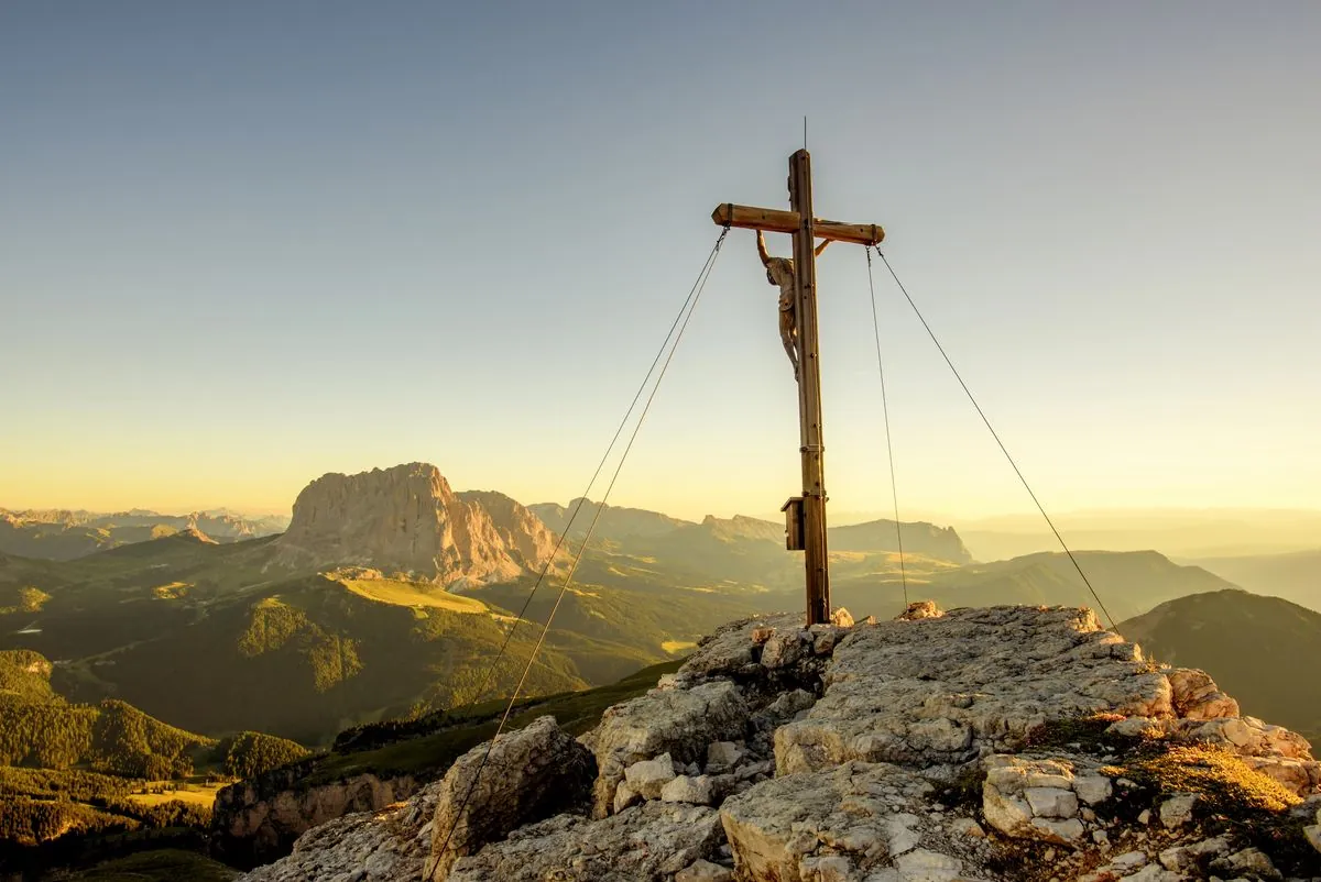 Gipfelkreuz im Abendlicht, dahinter der Langkofel