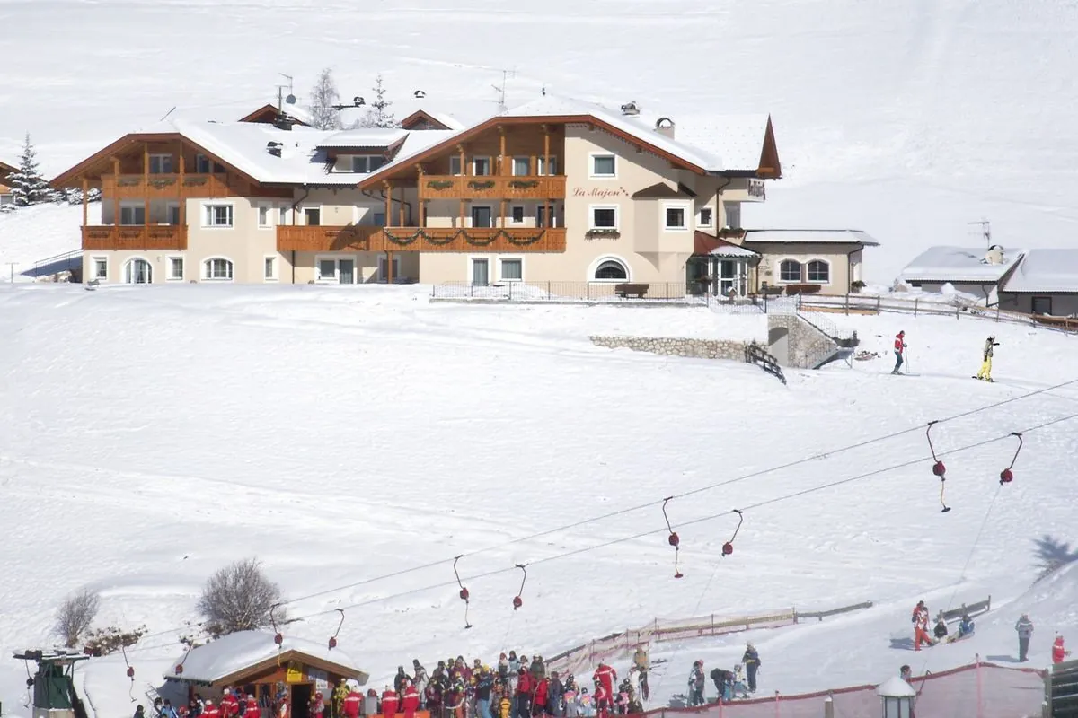 Das Garni La Majon im Schnee, davor der Cadepunt-Lift mit Bügeln und Skifahrer am Übungshang