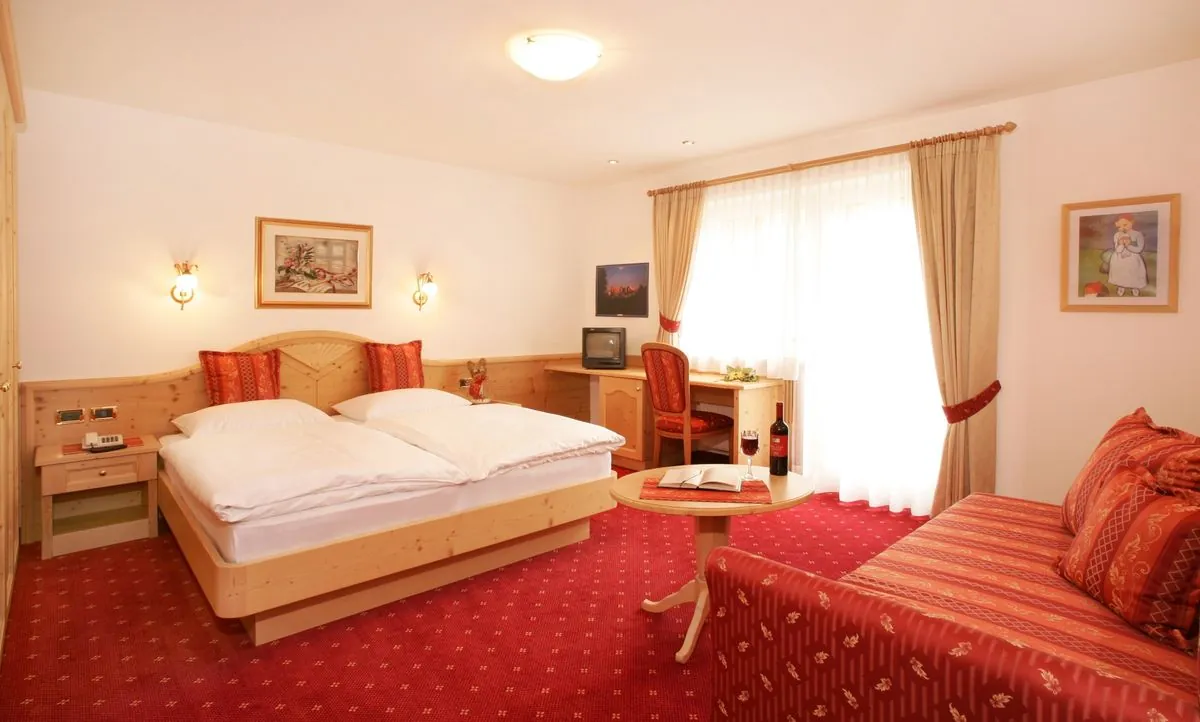 Komfortzimmer mit Doppelbett, Sitzbank und rotem Teppich
