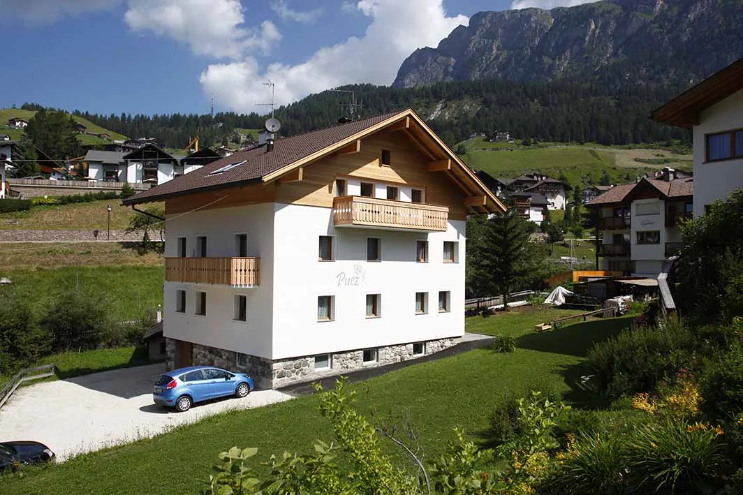 Haus Puez im Sommer, weiß mit Holzbalkon