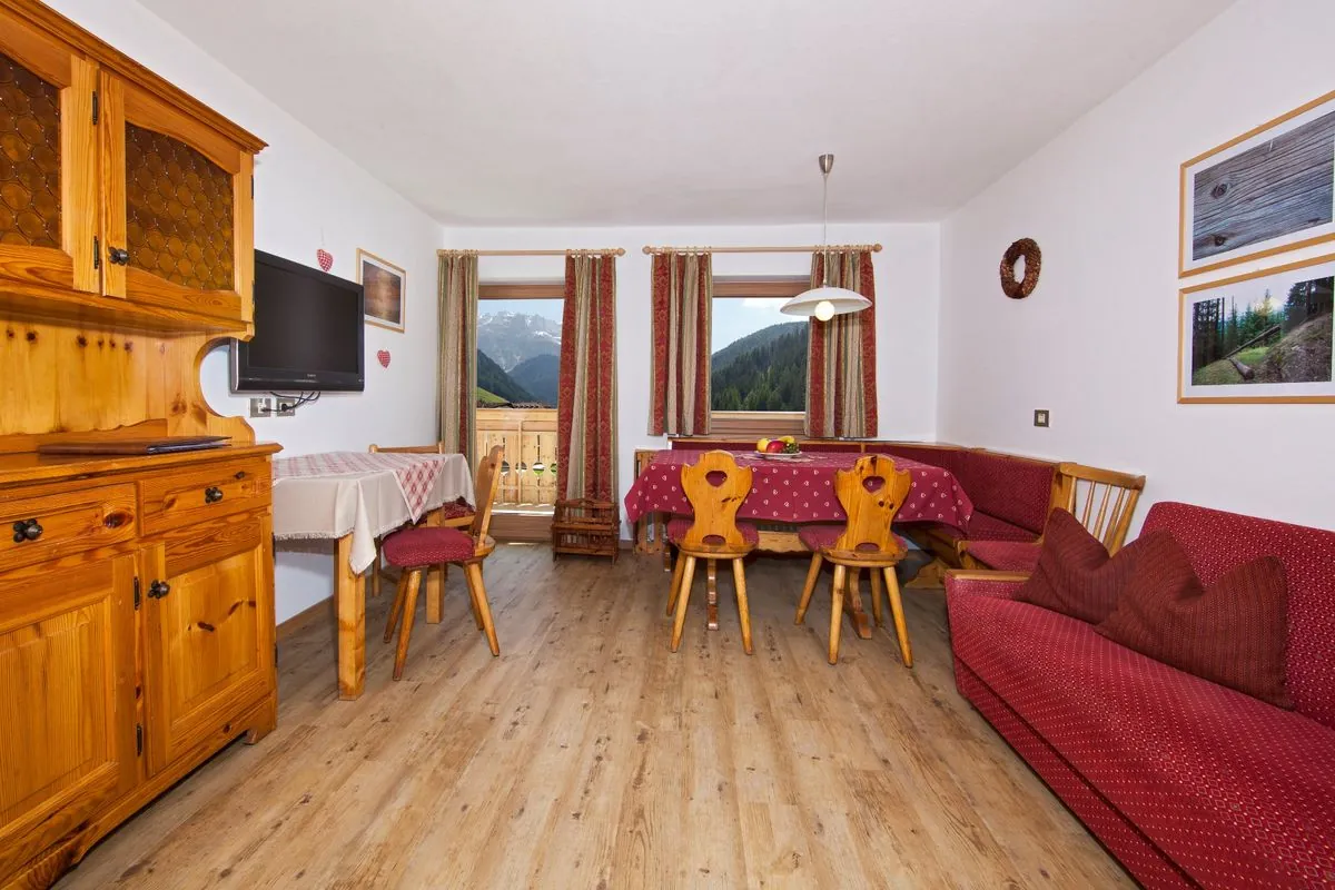 Wohnzimmer im Apartment Puez mit Holzboden und roter Couch