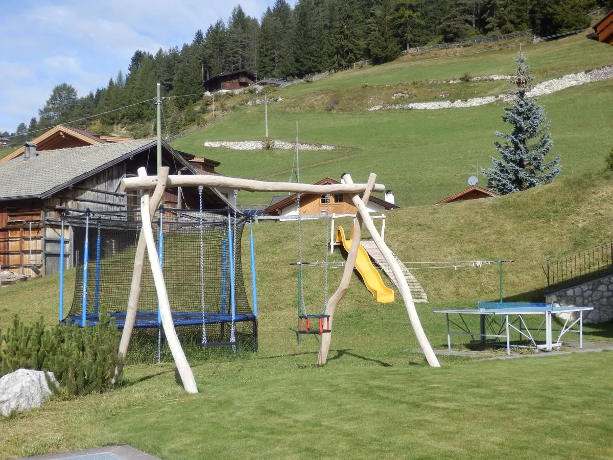 Kinderspielplatz mit Rutsche, Schaukel und Tischtennisplatte hinter dem Haus