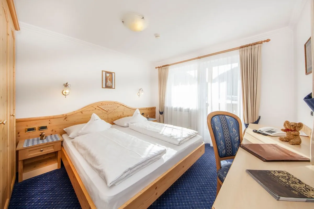 Schlafzimmer mit Doppelbett, Schreibtisch und Balkontür
