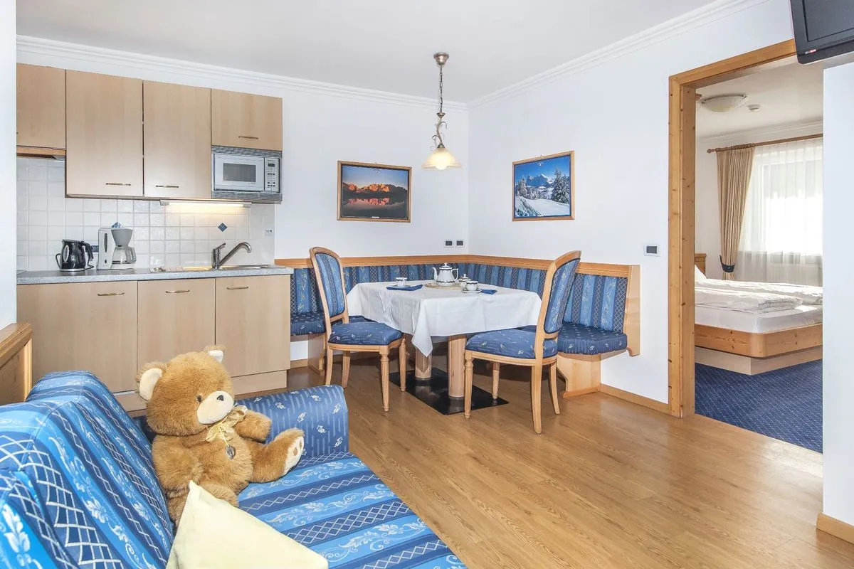 Wohnzimmer einer Zweizimmerwohnung mit Sitzecke, Kochnische und Blick ins Schlafzimmer